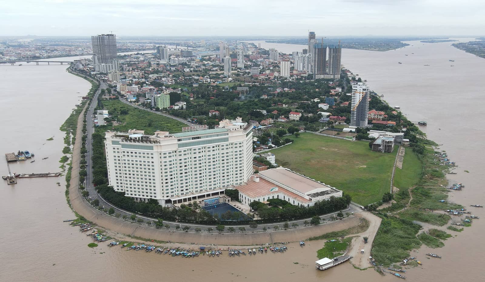 The Chroy Changvar peninsula from the air, water on both sides where the rivers meet, with the Phnom Penh skyline across the channel