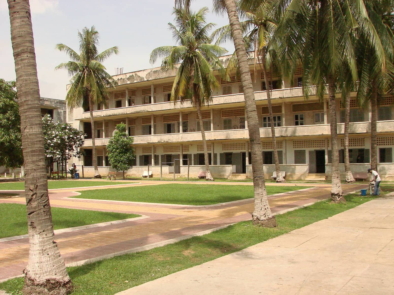 The former school buildings of Tuol Sleng in Phnom Penh, three storeys of open balconies around a quiet grass courtyard planted with palms